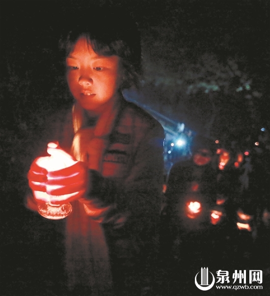  走在山路上，孩子小心翼翼地捧着烛火。