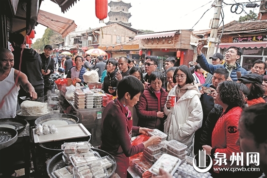     昨日，市区西街迎来游客高峰，在一家传统小吃店门口，游客排队购买。 （陈晓东 摄）