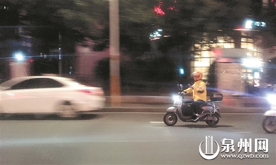 一名送餐人员一边骑车一边看手机 一名送餐人员一边骑车一边看手机