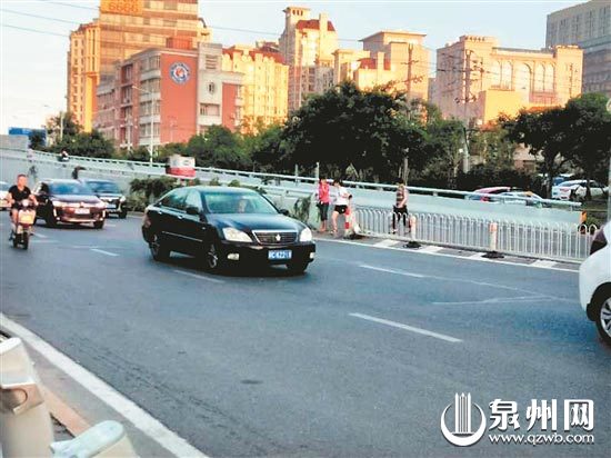  在千亿商业城对面马路，不少人无视车流翻越护栏。