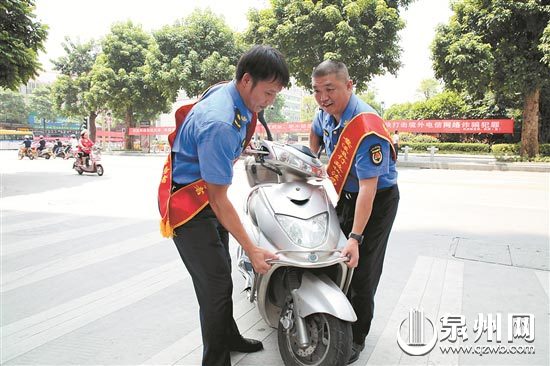 陈毅志（右）将电动车移到规范停车区内