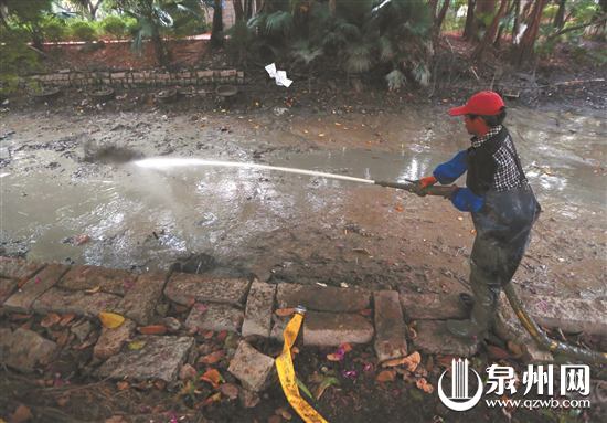 工作人员用高压水枪冲洗淤泥