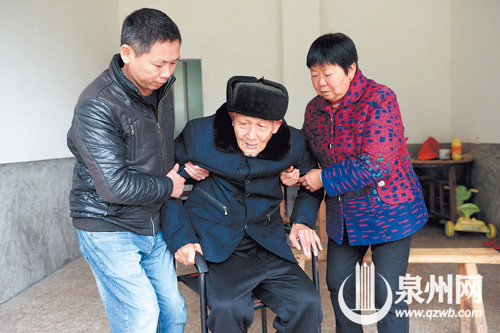 黄秀红在儿子帮助下，将老伴扶到客厅坐着。