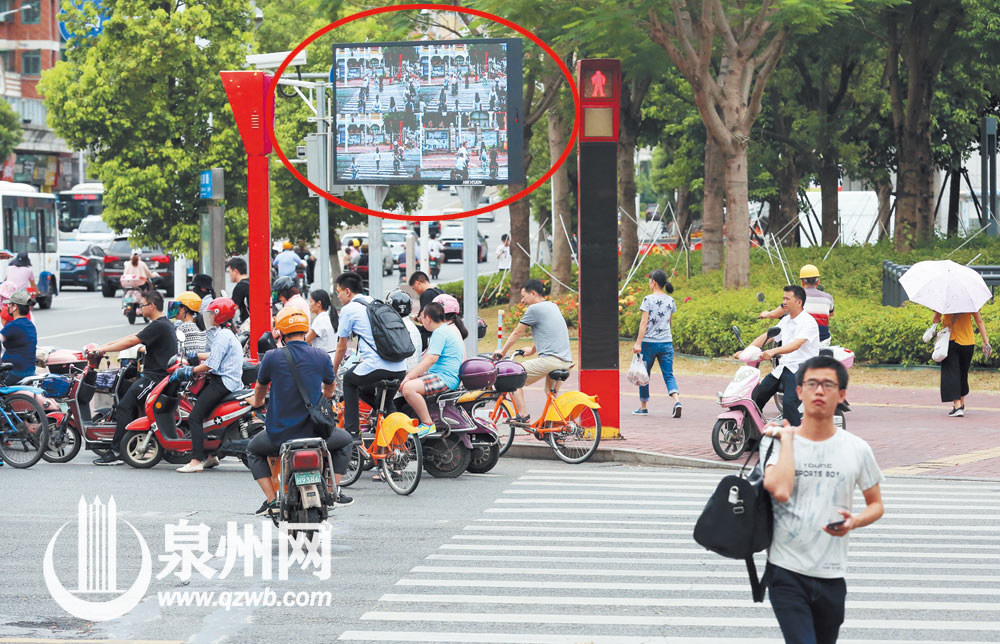 行人闯红灯将被抓拍，并曝光在屏幕上（图中画圈处）。