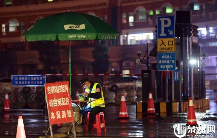 2月16日凌晨3点40分，在丰泽广场的检查点，一名保安正在雨中的伞下泡面。（陈英杰 摄）