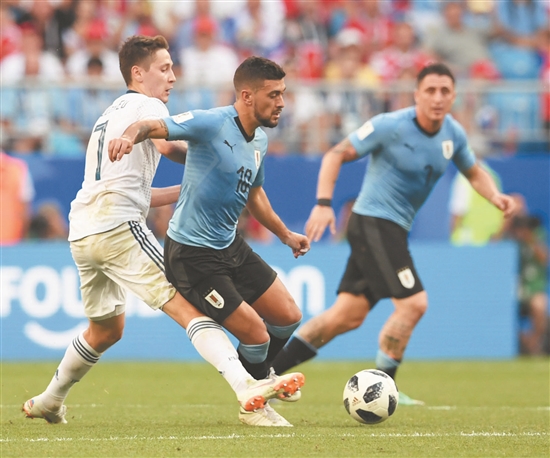 乌拉圭队球员阿拉斯卡埃塔（中）与俄罗斯队球员库兹亚耶夫（左）在比赛中拼抢。 （新华）